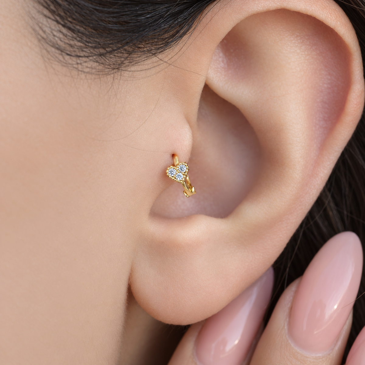 Gold mini heart hoop earring worn in tragus piercing