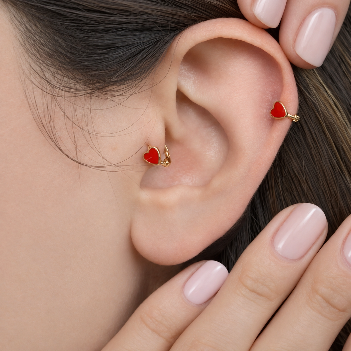 Gold hoop with a red heart worn on the ear