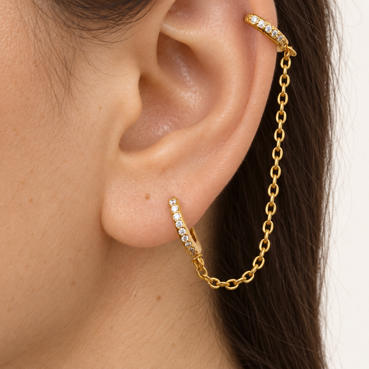 Gold double hoop ear chain earring worn between helix and lobe