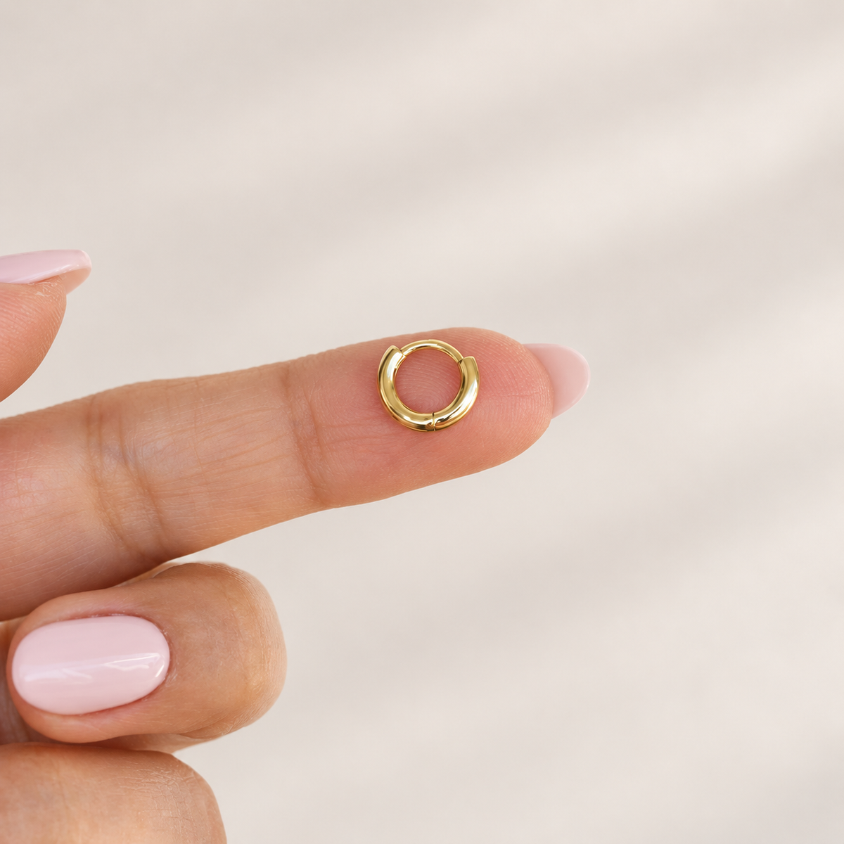 Gold hoop ring held between fingers, product detail