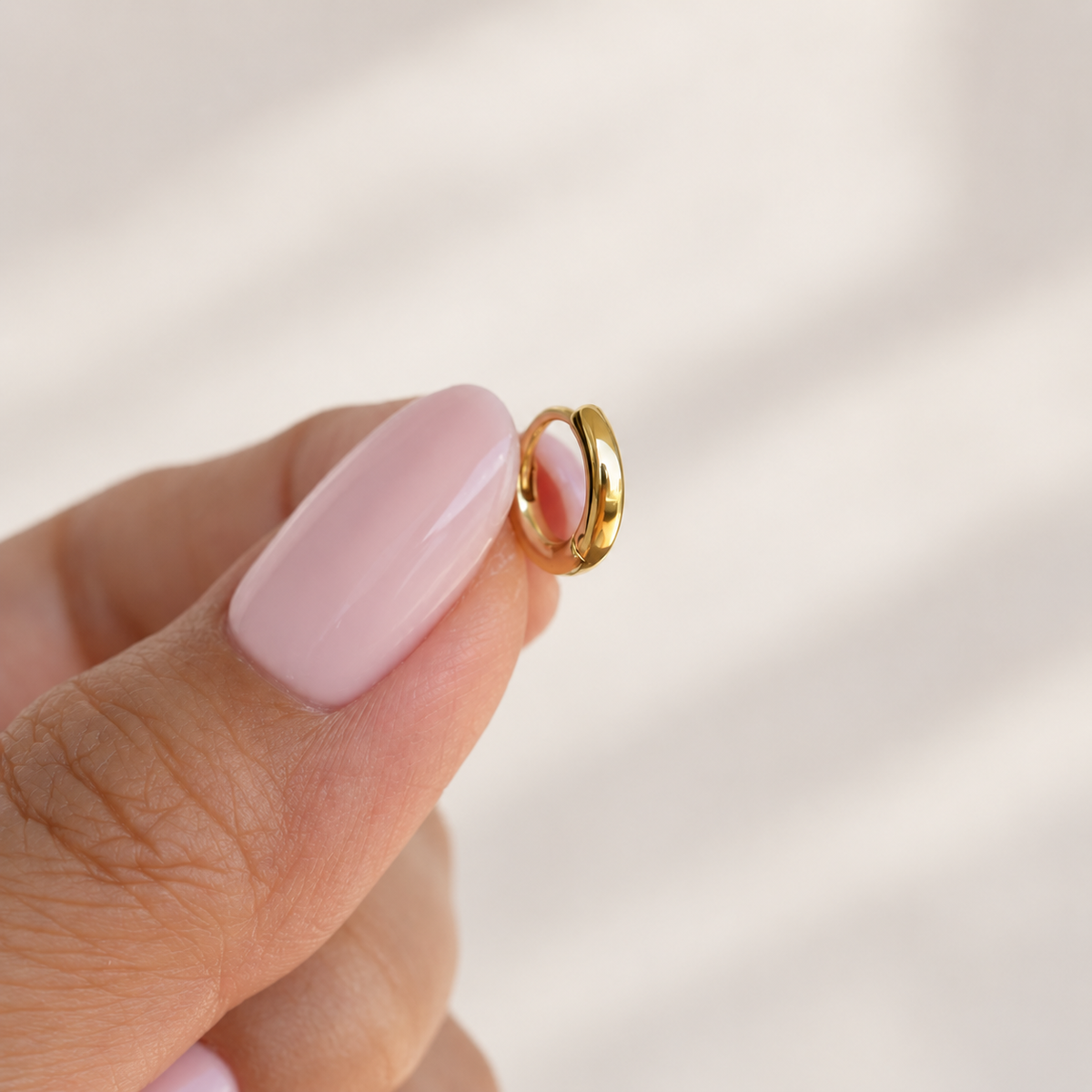 Gold hoop ring held between fingers, product detail