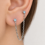 Silver star ear chain earring worn across two ear piercings