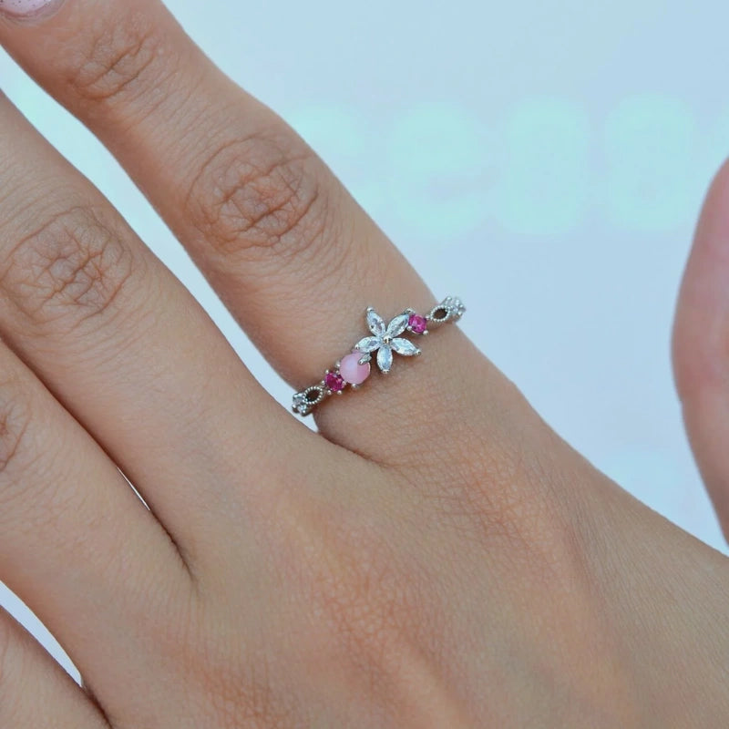 Silver flower adjustable ring with pink stones, worn on a finger