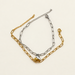 One gold-coloured and one silver-coloured elongated-link bracelet with half-heart charms laid side by side.