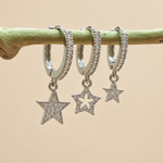 Three silver-coloured hoops with clear-stone star dangles hanging in a row from a green stem.