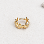 Gold-tone leaf hoop earring with clear-stone details on a pale surface.