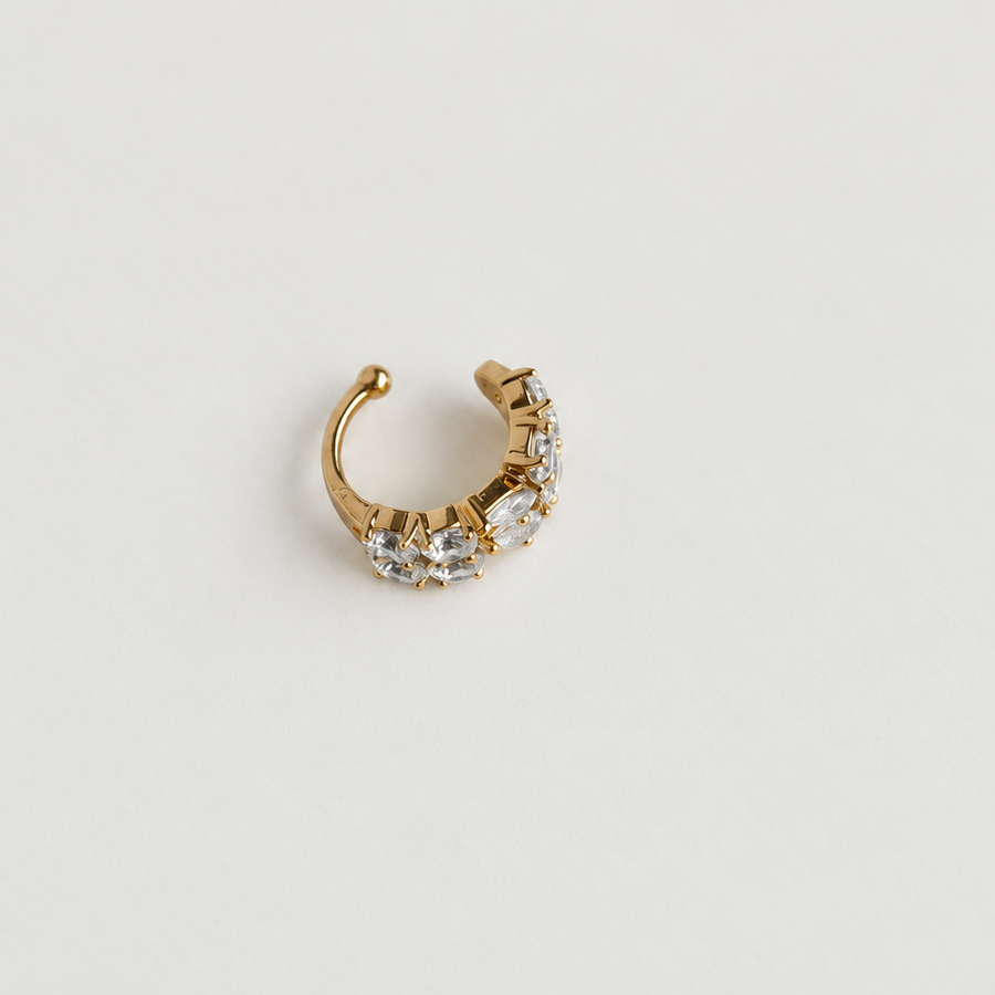 Gold-tone ear cuff with clear stones on a white surface, showing the open back.