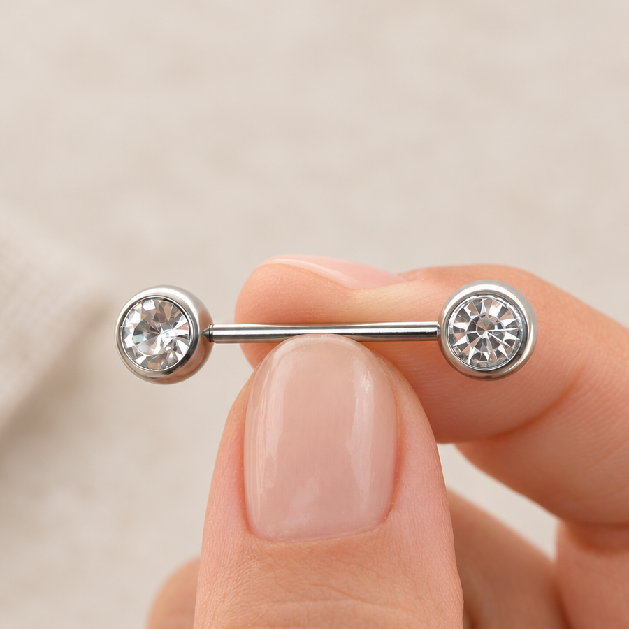 Silver-tone straight barbell held between fingers, with a round clear stone at each end.