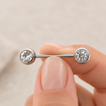 Silver-tone straight barbell held between fingers, with a round clear stone at each end.