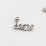 Silver-tone curved star-cluster piercing stud on a pale surface, with its straight post and ball back visible.