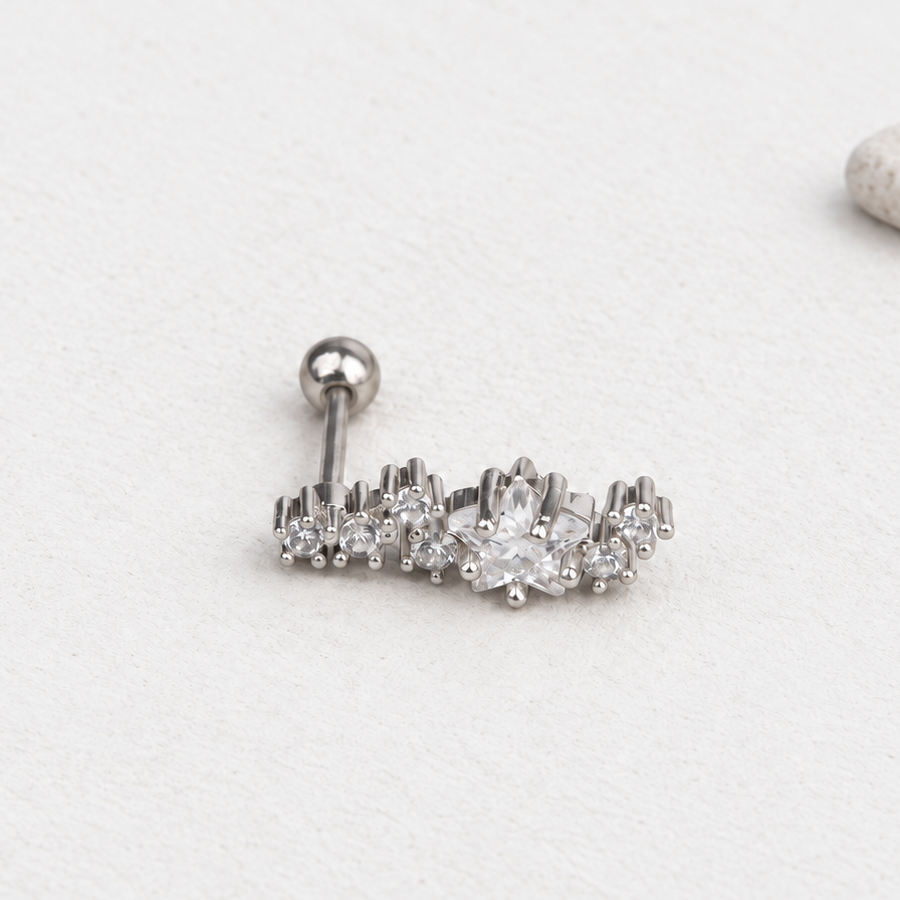 Silver-tone curved star-cluster piercing stud on a pale surface, with its straight post and ball back visible.