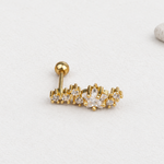 Gold-tone curved piercing stud with a clear star-shaped centre, smaller stones and a ball back on a pale surface.